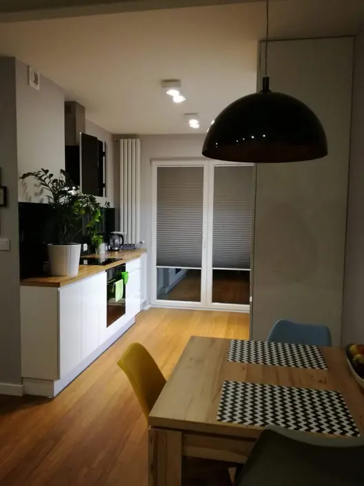 Kuchnia otwarta na jadalnię z lampą wiszącą nad stołem