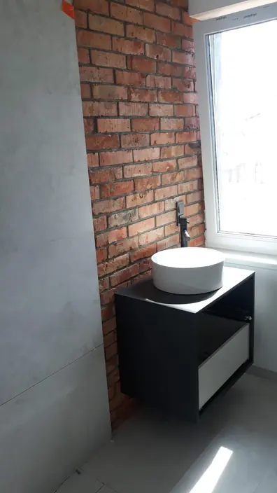 Ściana z betonu architektonicznego obok pasa cegły, umywalka nablatowa