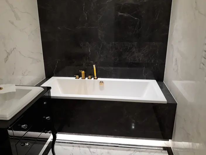 Wanna w obudowie z czarnego marmuru ze złotą baterią wannową