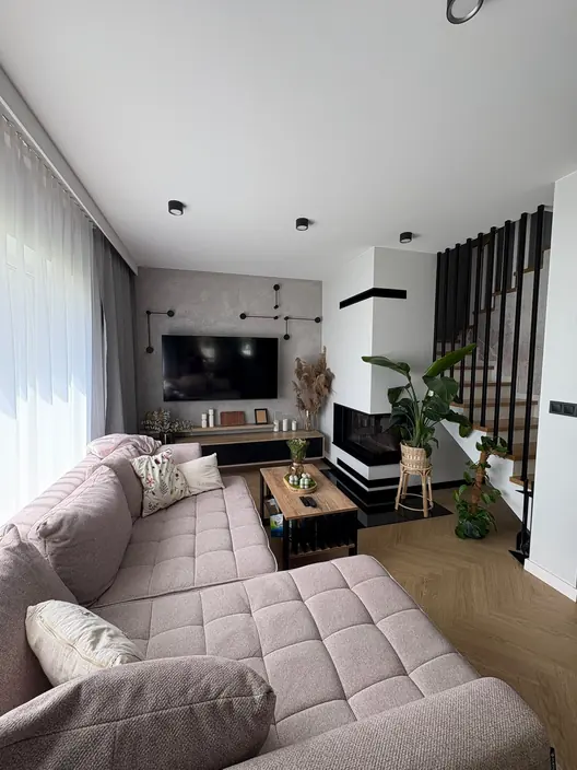 Salon z kominkiem i schodami z metalową balustradą