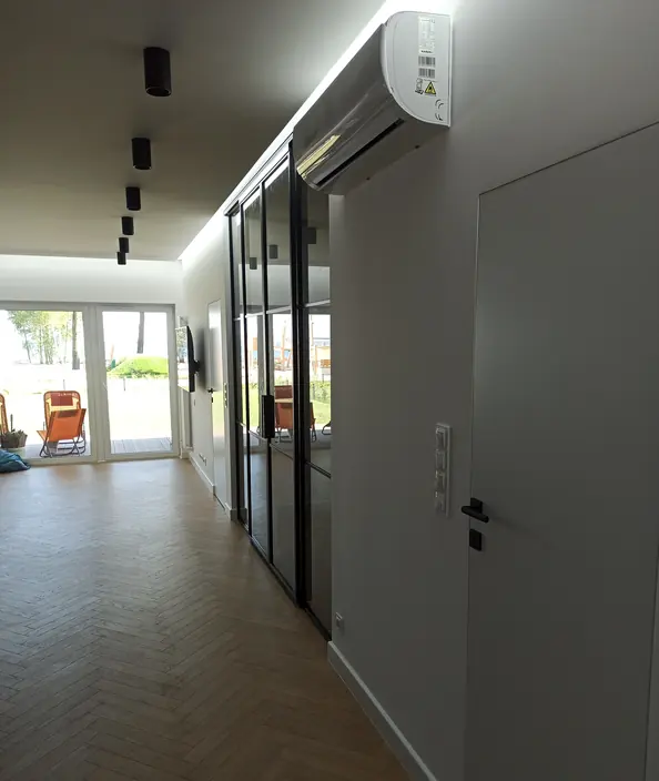 Salon z zabudową wnękową zamkniętą przeszklonymi drzwiami loftowymi