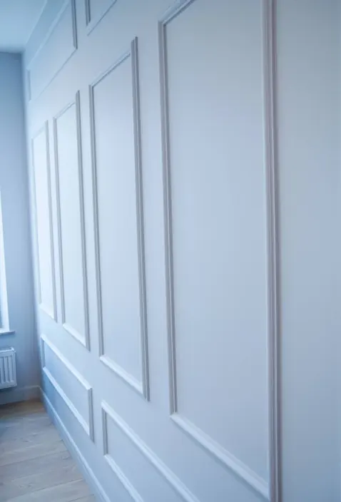 Ściana z listwami dekoracyjnymi w układzie ramek, pomalowana na biało